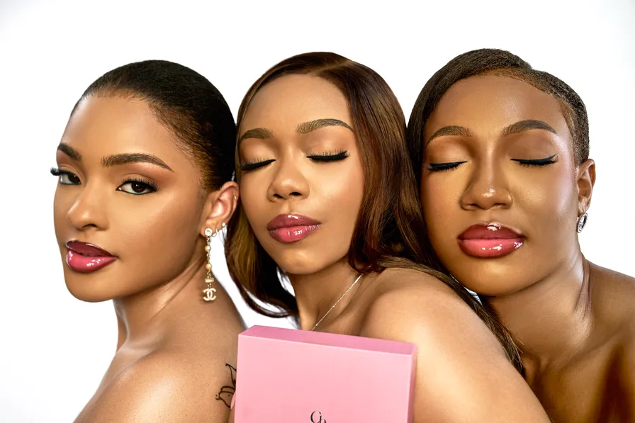 Three models with different skin tones, each wearing glossy lips, holding a pink Chardonnay Beauty box